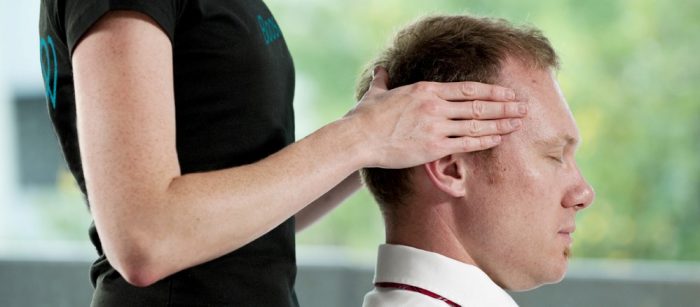 Massage therapist / Masseuse massaging man's head in an office